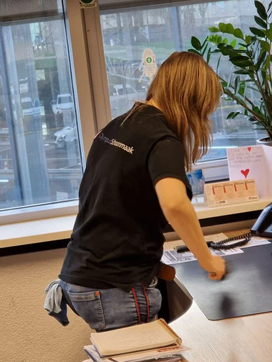 Olympus-medewerker neemt een bureau af met een doek