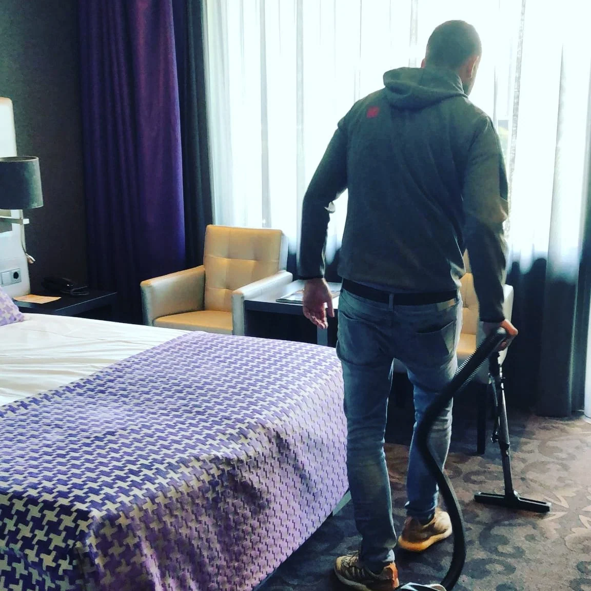 Olympus-medewerker stofzuigt de tapijtvloer naast een bed