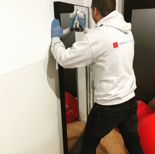 Olympus-medewerker met blauwe handschoenen reinigt een spiegel