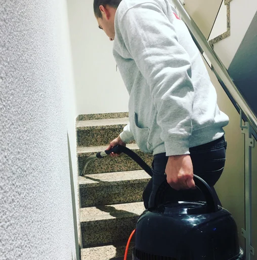 Olympus-medewerker stofzuigt de treden van een trappenhuis