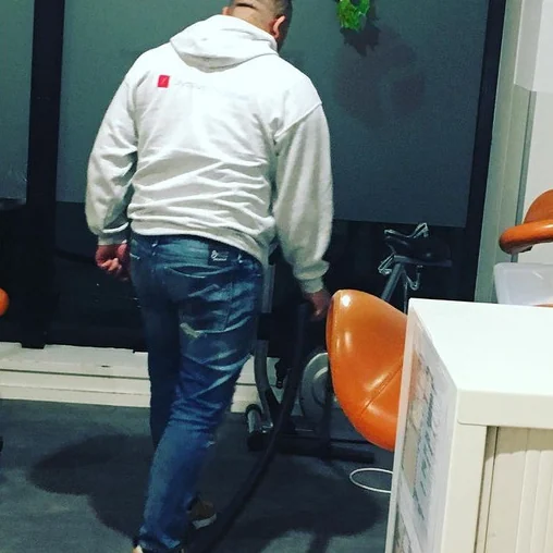 Olympus-medewerker stofzuigt tussen de stoelen van een wachtruimte