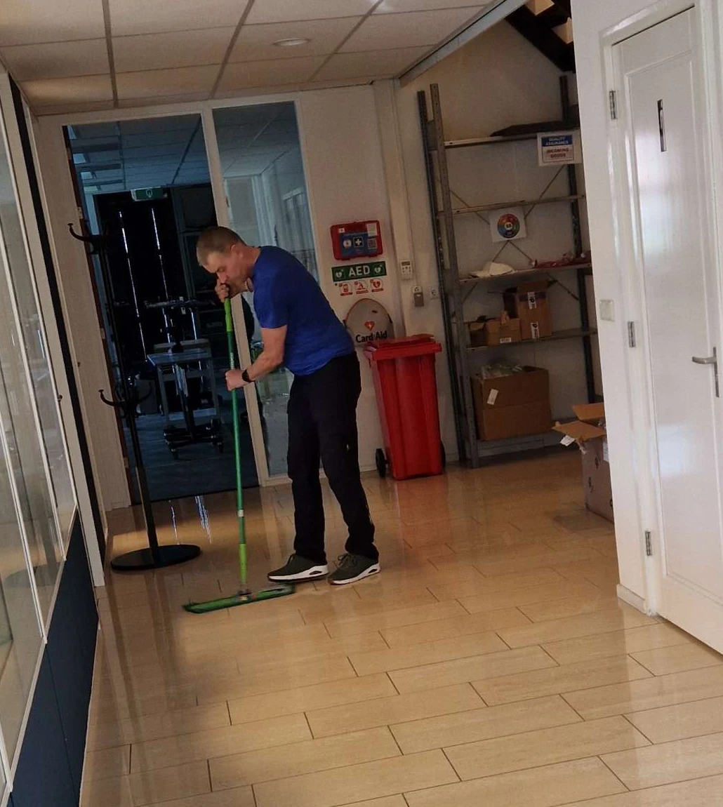 Olympus-medewerker reinigt de vloer van een gang met een vlakmop